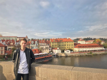 Student stoi z lewej strony. W tle widok na miasto.