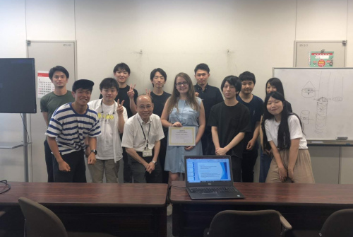 Grupa studentów i wykładowców stoi w sali wykładowej