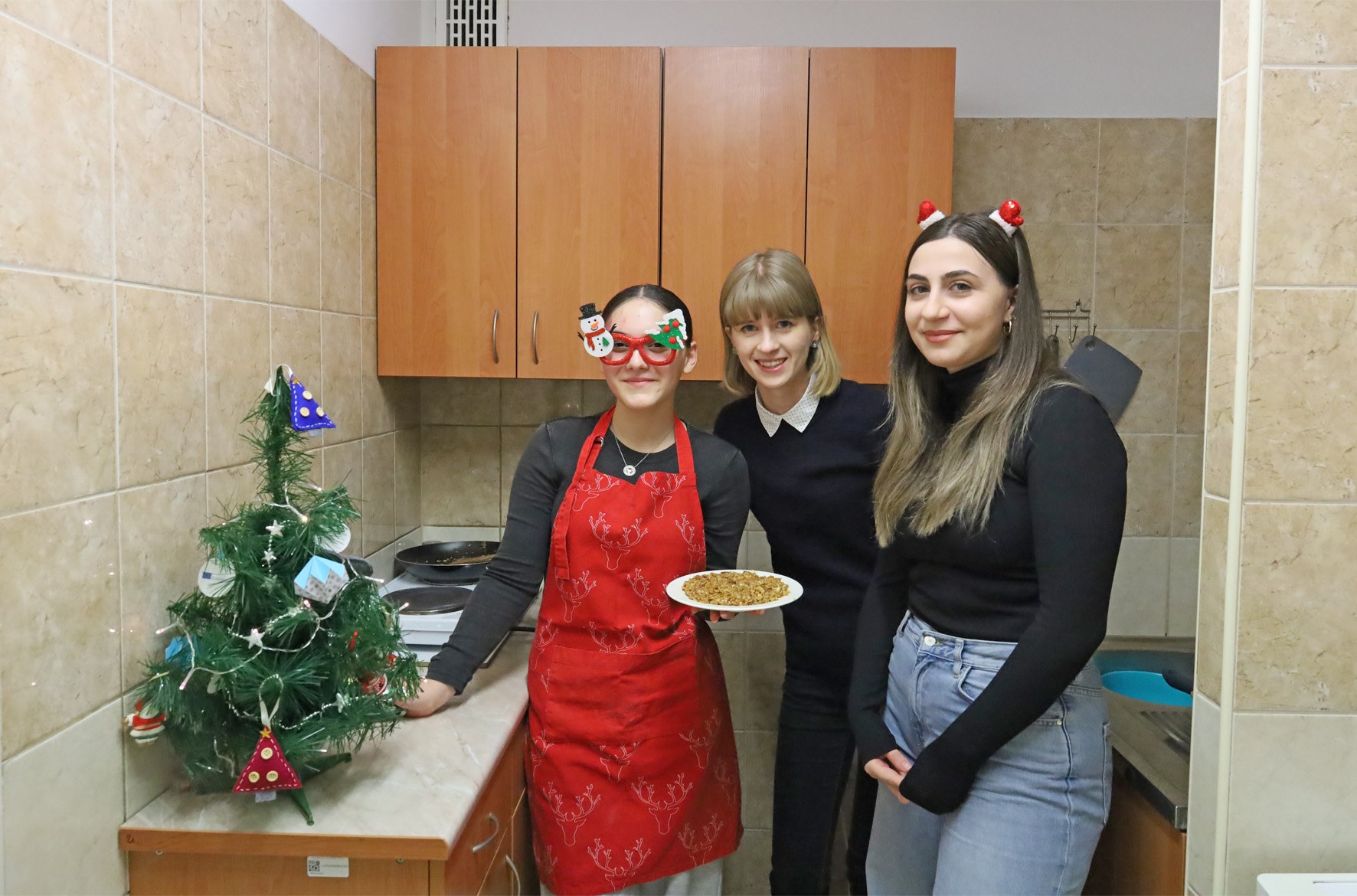 Zdjęcie grupowe. Trzy kobiety stoją w kuchni i pozują do zdjęcia. Jedna z nich trzyma talerz.
