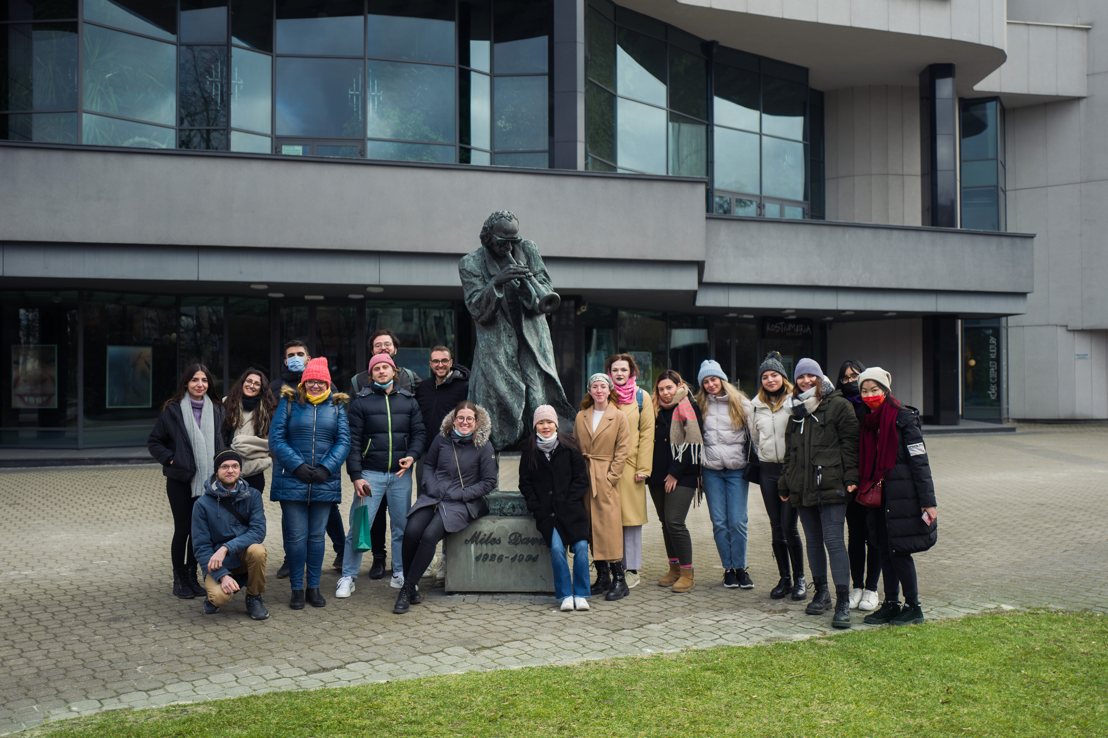 Zdjęcie grupowe studentów. W tle rzeźba i budynek Kieleckiego Centrum Kultury.