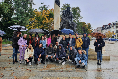 Zdjęcie grupowe.  Studenci stoją. W tle rzeźba Quo Vadis.