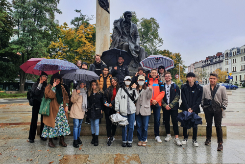 Zdjęcie grupowe. Studenci stoją. W tle rzeźba Quo Vadis.