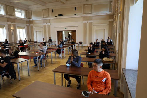 Studenci siedzą i słuchają prezentacji.