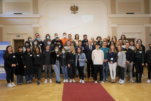Liczna grupa ludzi stoi w trzech rzędach w głównej auli.